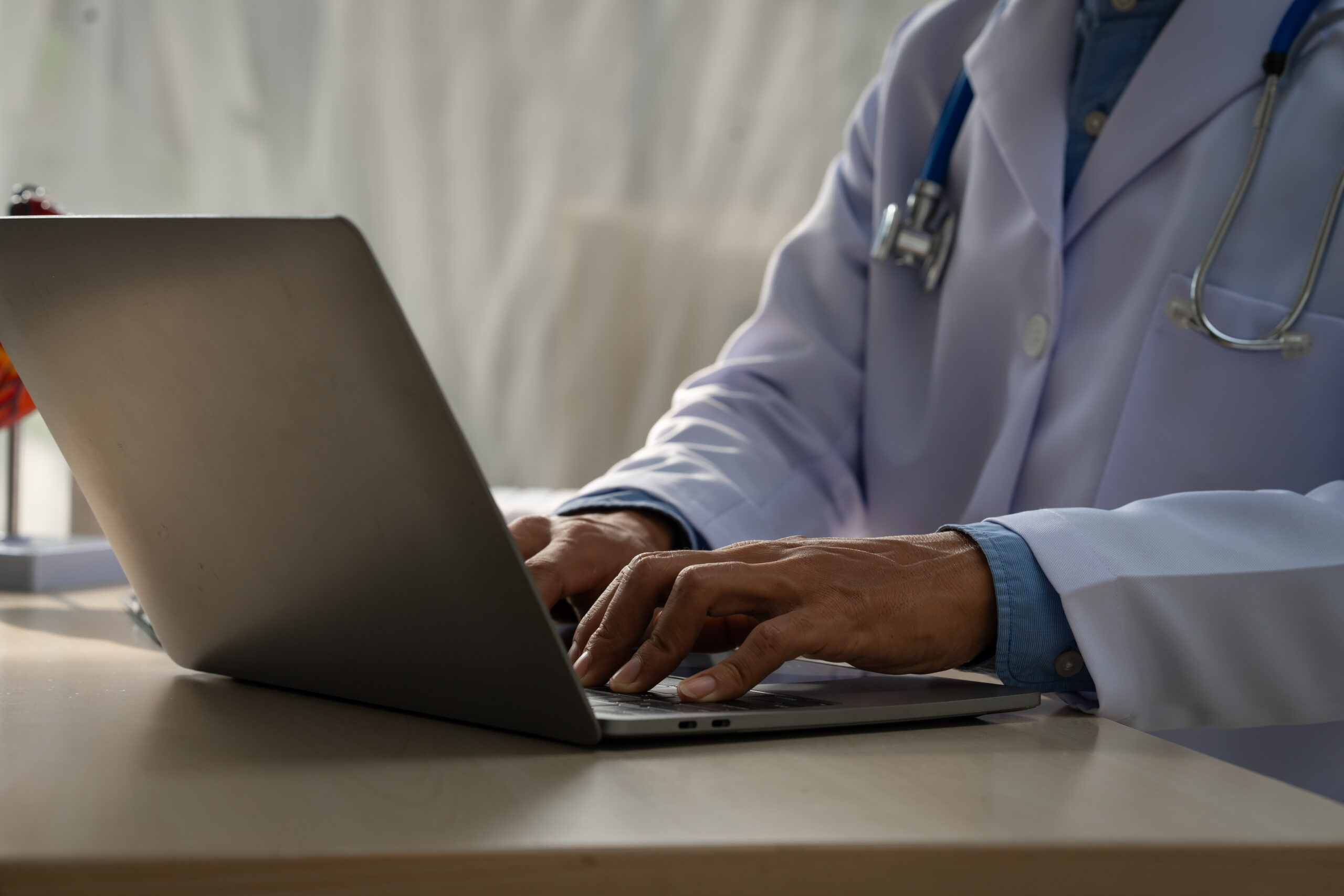 A male doctor sits at a desk in the heart clinic, consulting onl
